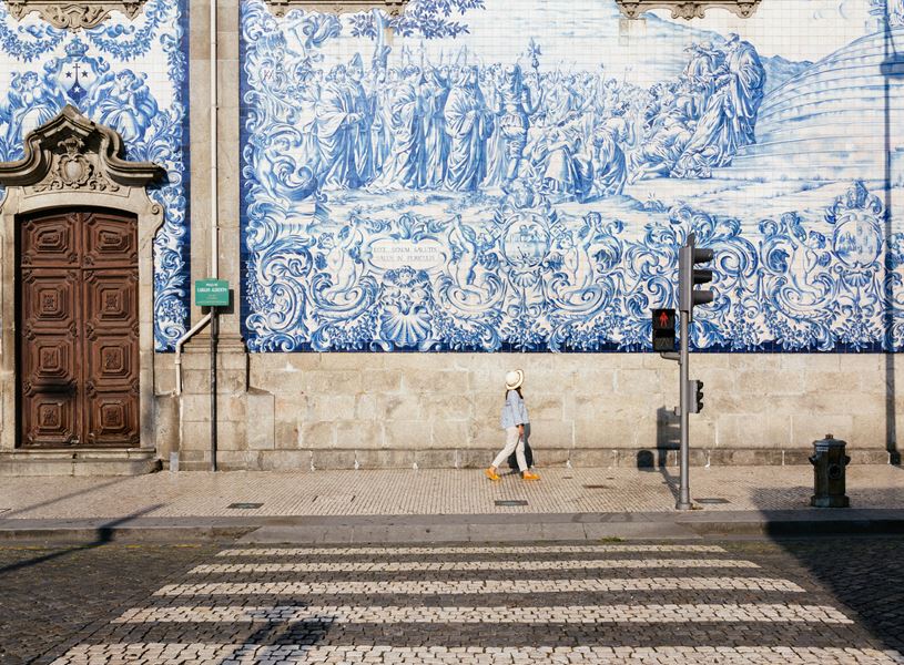 Woman walking past azulejos wall Porto, Portugal