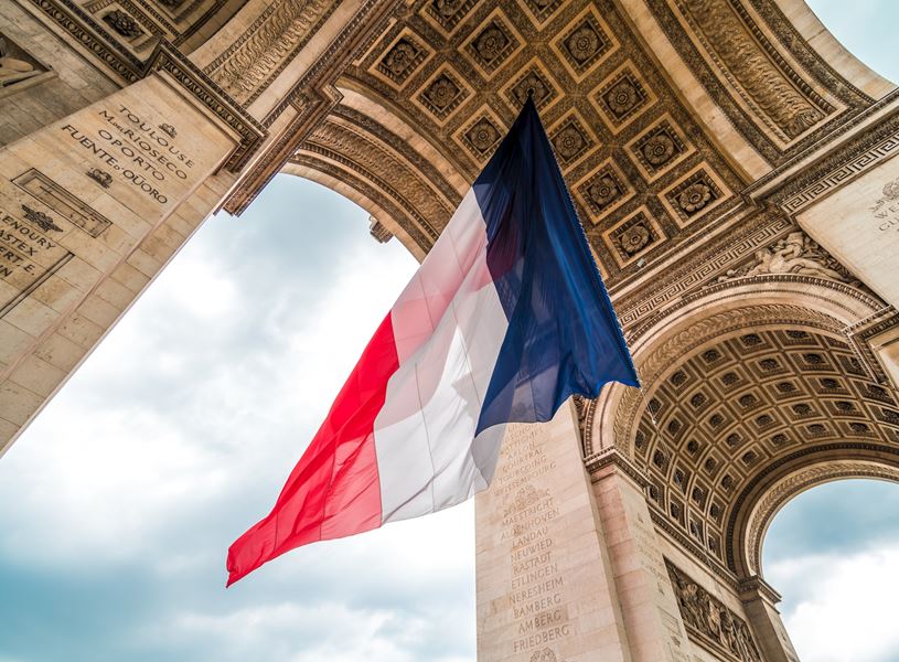 The French flag waving at the Arc de Triomphe monument in Paris, France