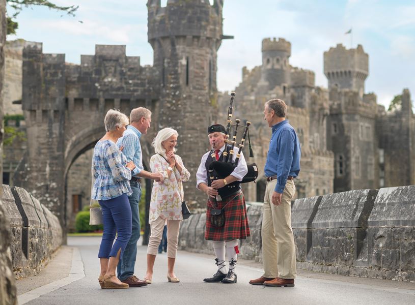 Bagpiper plays for guests on the drawbridge at Ashford Castle, Ireland