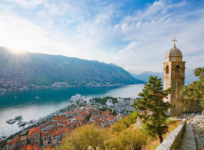 Panoramic view of Kotor Bay in Montenegro with church tower, red rooftops and cruise ship
