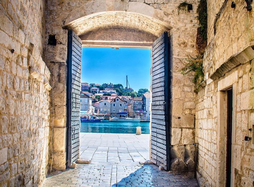 Gate framing the waterfront and Old Town in Trogir, Croatia