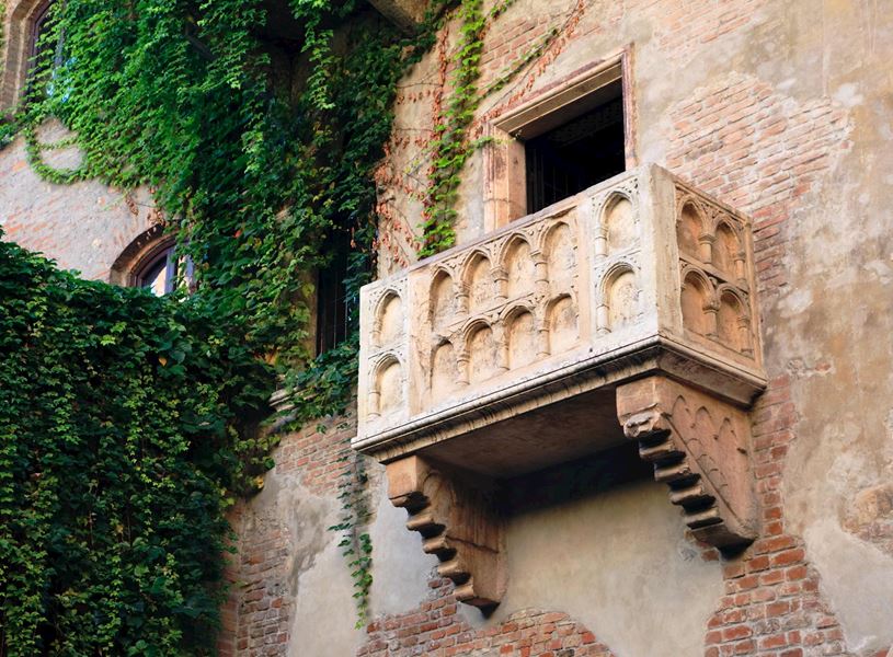 Juliet’s balcony in Verona with stone design and ivy-covered brick wall