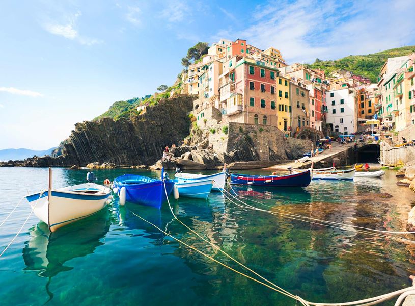 Coloruful boats moored in clear turquoise water at Riomaggiore, Cinque Terre