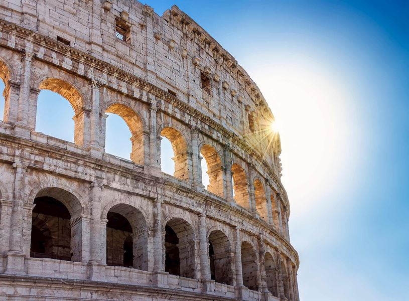 Close-up of Colosseum arches with bright sunburst in Rome