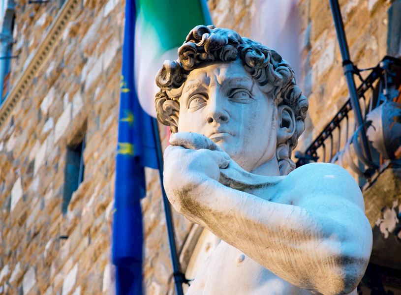 Michelangelo’s David statue in Florence with Italian and EU flags behind