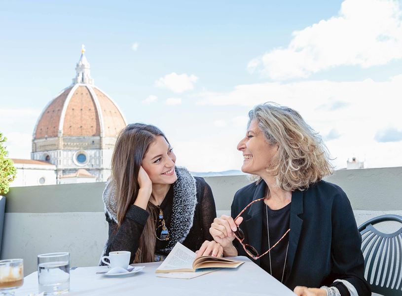 Two people sitting outdoor with Duomo Santa Maria del Fiore in background