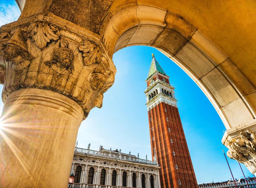 View of St. Mark’s Campanile in Venice framed by stone arch in Venice, Italy