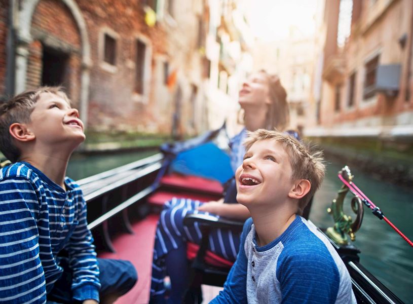 Children sitting inside gondola on Venetian canal in Venice, Italy