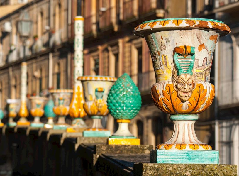 Row of colourful ceramic vases and pinecone ornaments on stone balustrade