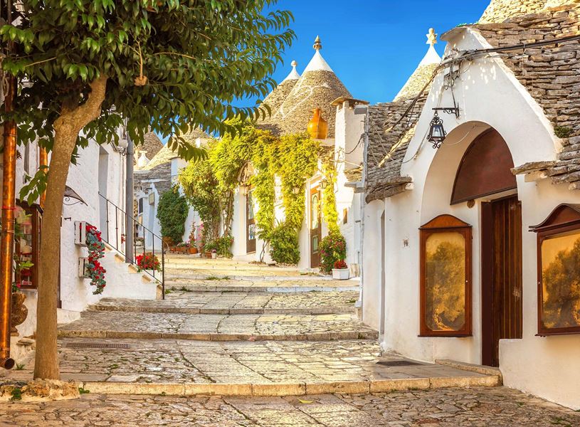 Alberobello street lined with traditional white trulli houses and greenery