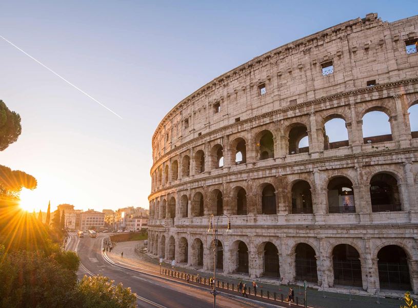 Colosseum in Rome at sunrise with glowing arches and sunburst effect