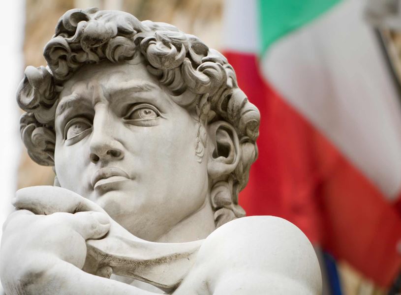 Close-up of Michelangelo’s David statue with Italian flag in background