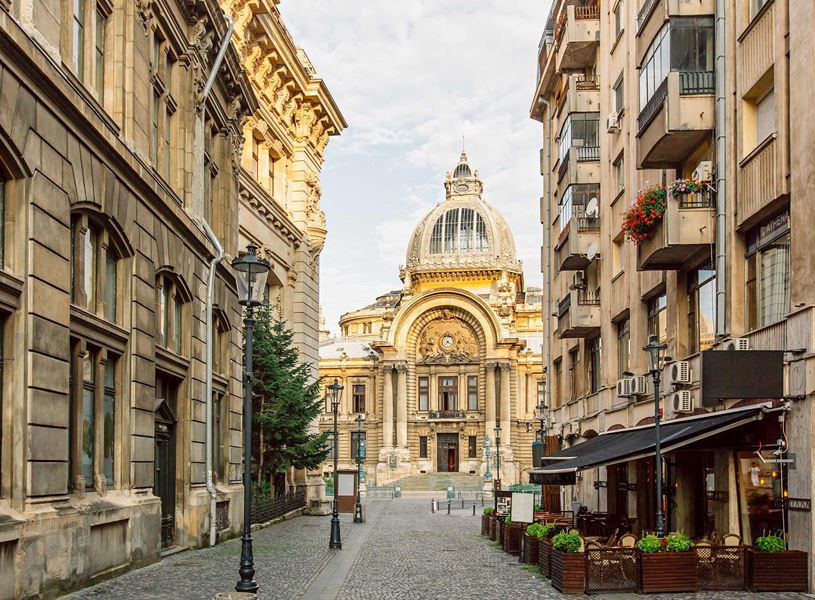 Historic CEC Palace viewed from cobblestone street lined with buildings in Bucharest, Romania