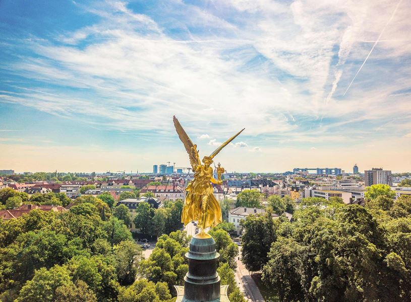 Friedensengel golden angel statue overlooking city and trees in Munich