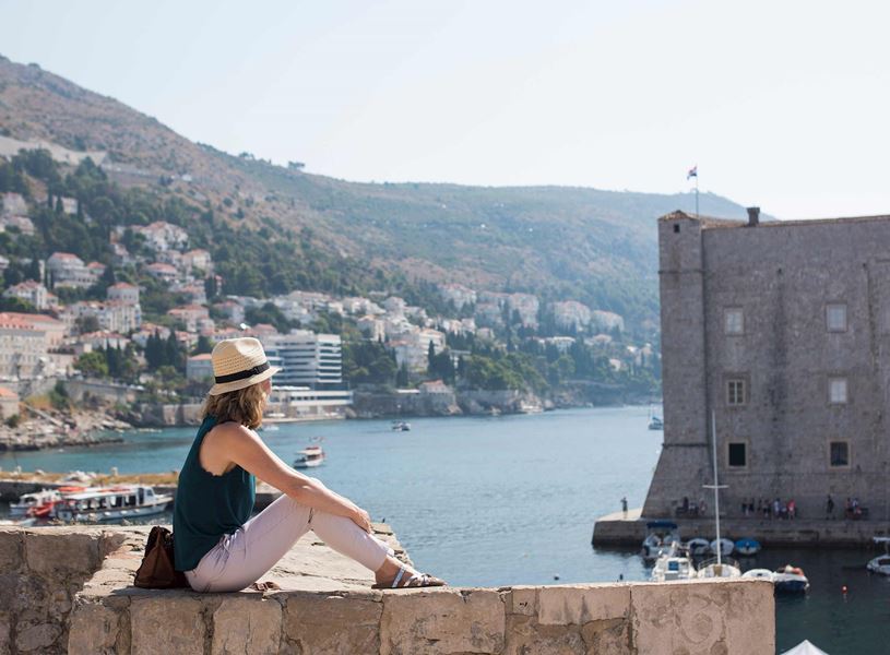 Traveller sitting on wall overlooking Dubrovnik, Croatia