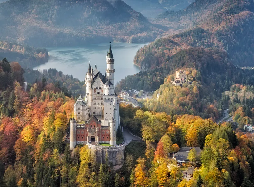 Neuschwanstein Castle surrounded by autumn forest and mountains