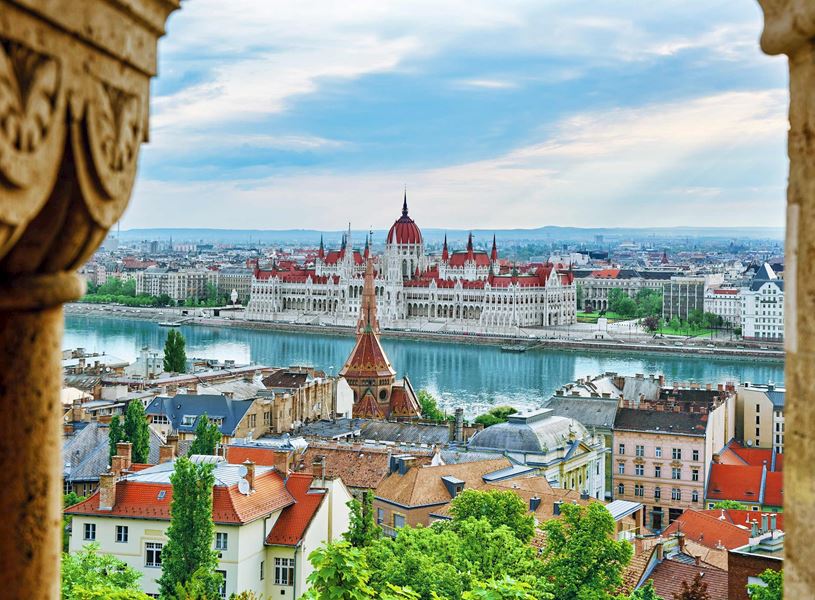 Panoramic view of Hungarian Parliament beside Danube River with rooftops and trees