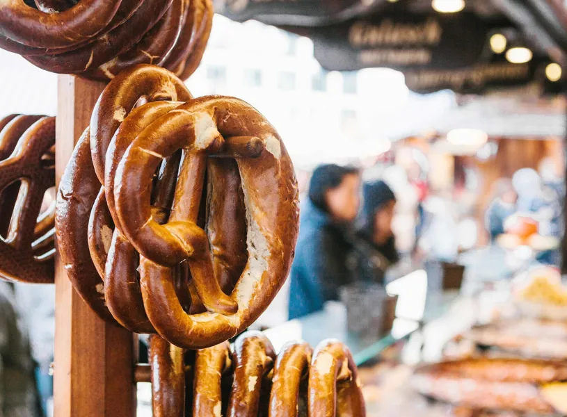 Pretzels hanging on wooden stand at outdoor market stall