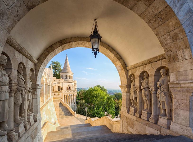 Stone archway at Fisherman’s Bastion framing turret, staircase and trees.