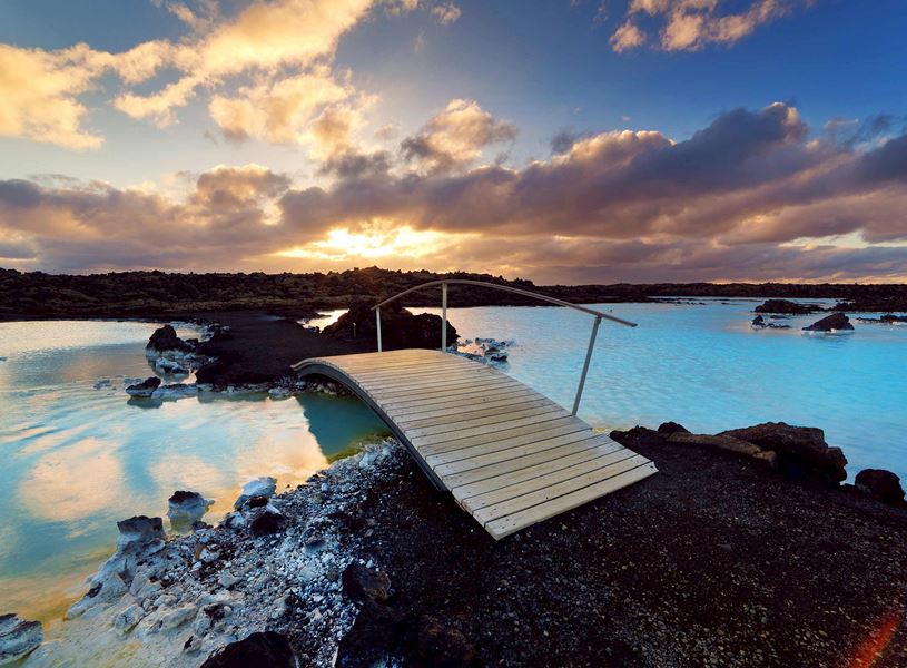 Wooden bridge over the Blue Lagoon and rocky landscape at sunset