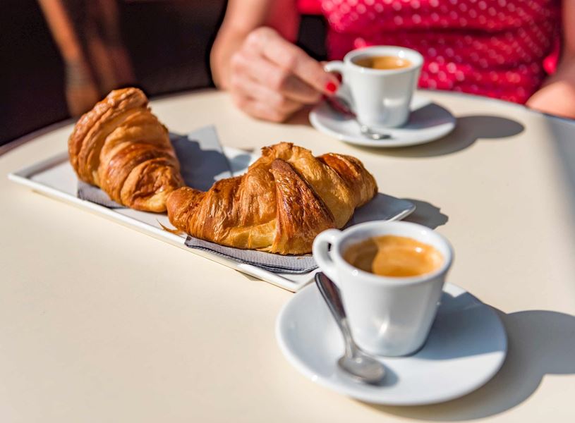 Two croissants and espresso cups on table