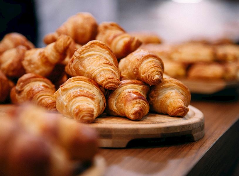 Freshly baked croissants stacked on wooden board