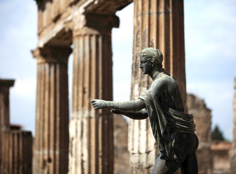 Statue at Temple of Apollo in Pompeii with ancient stone columns and ruins