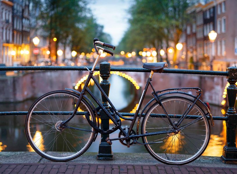 Black bicycle parked on Amsterdam canal bridge with arch lights
