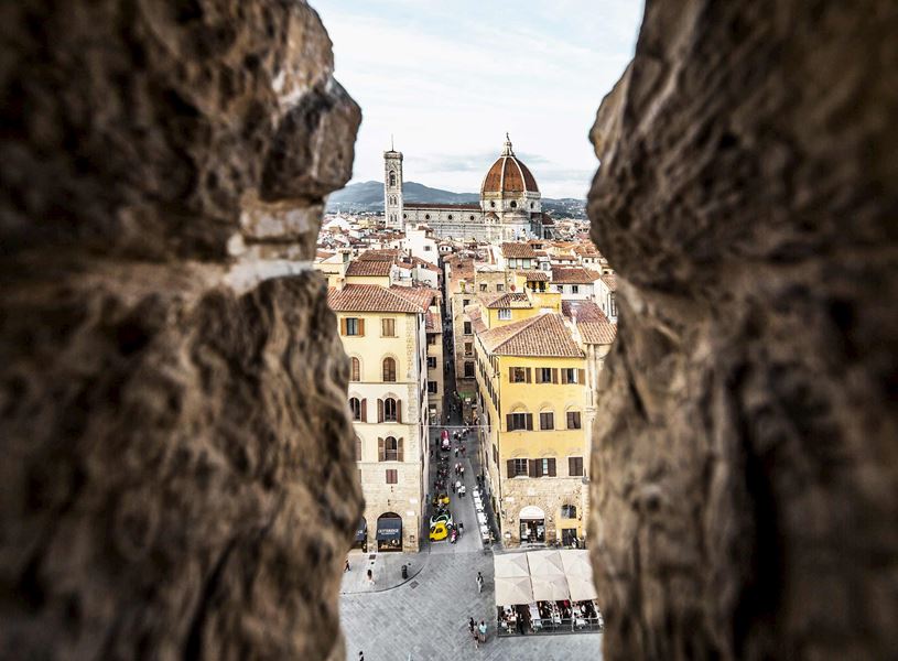 Florence cityscape with Duomo framed by stone archway overlooking rooftops