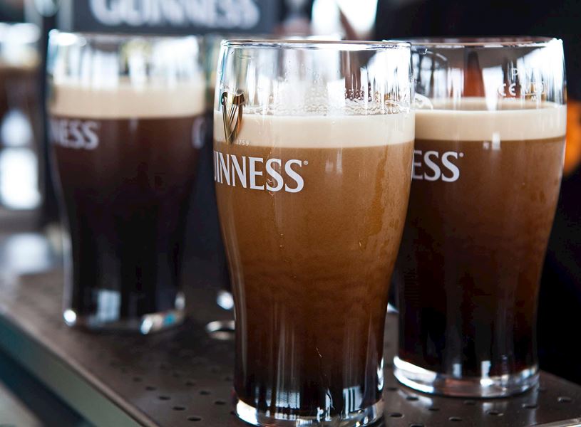 Guinness pints with creamy heads on metal bar surface