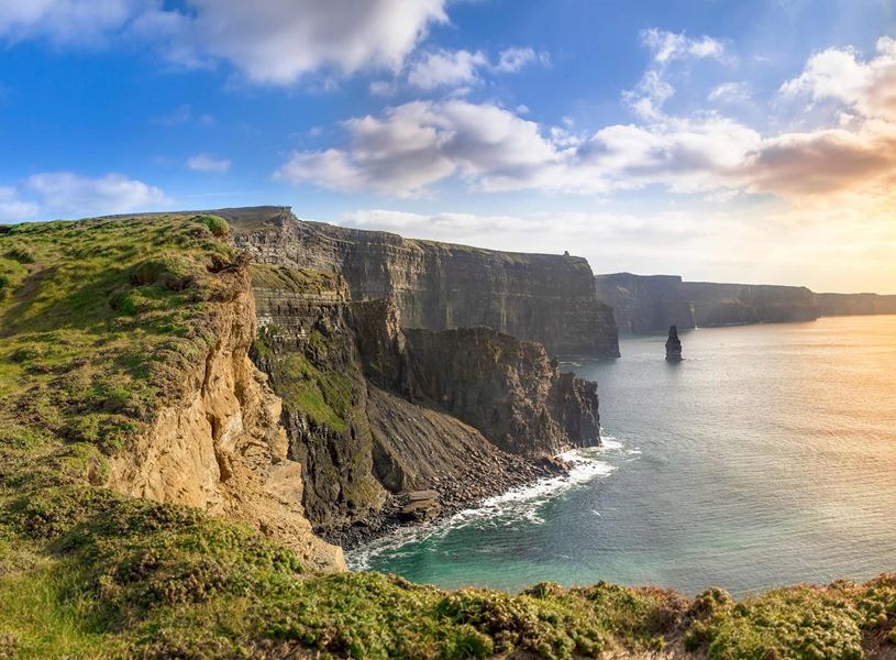 Cliffs of Moher with Atlantic Ocean view and grassy edge at sunset 