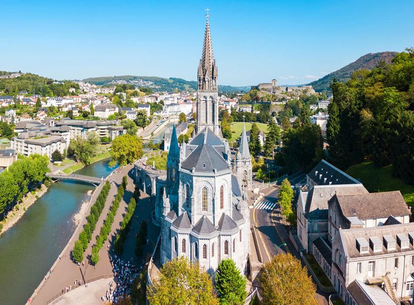 Aerial view of Lourdes sanctuary beside river and hills in France