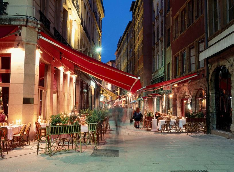 Lyon street with cafés, red awnings and evening lights