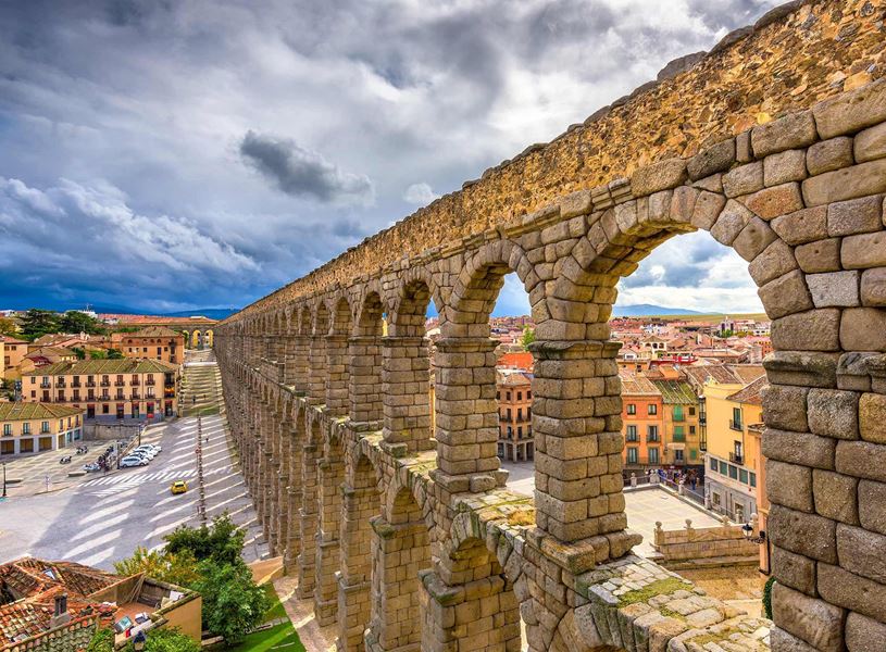 Ancient Roman aqueduct with stone arches overlooking city in Segovia, Spain