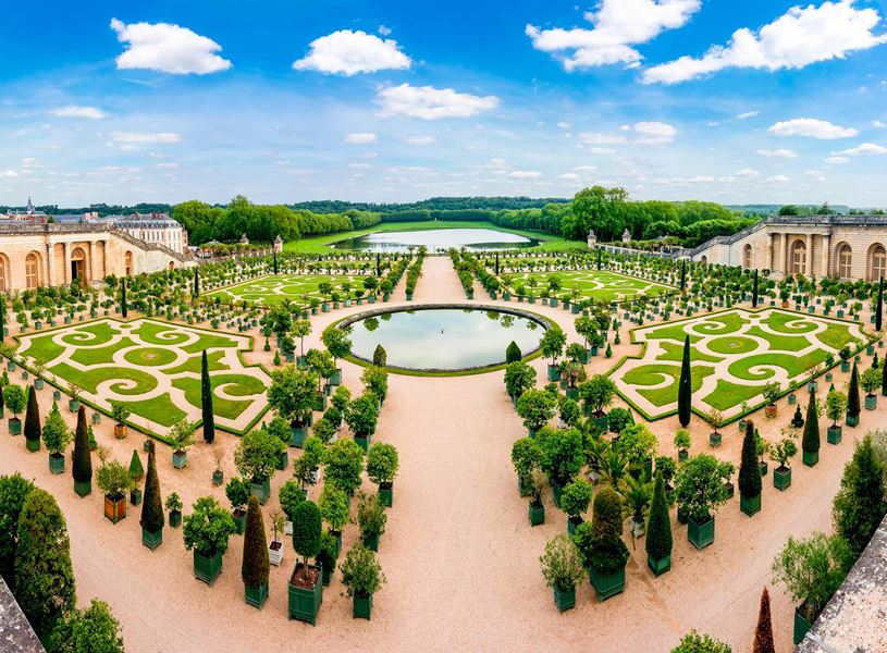Versailles garden with circular pond, manicured hedges and tree-lined paths