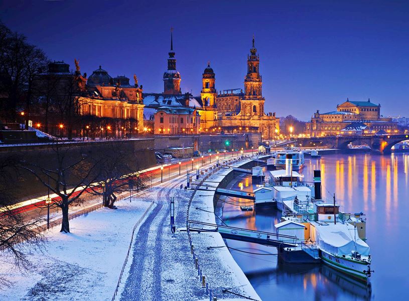 Dresden winter evening with snowy riverbank and illuminated historic buildings