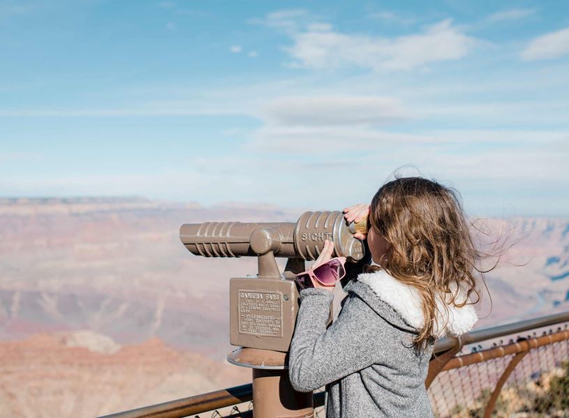 Girl looking through binoculars at Grand Canyon, USA