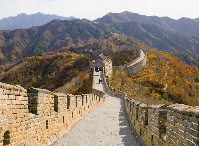 The Great Wall of China winding over forested hills on a sunny autumn day near Beijing, China
