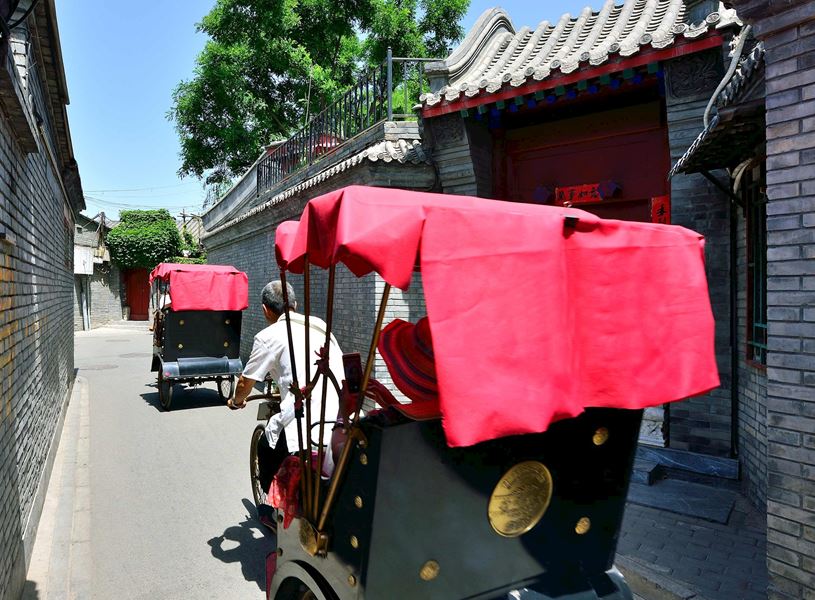 Rickshaws driving away along narrow street on sunny day, Beijing, China