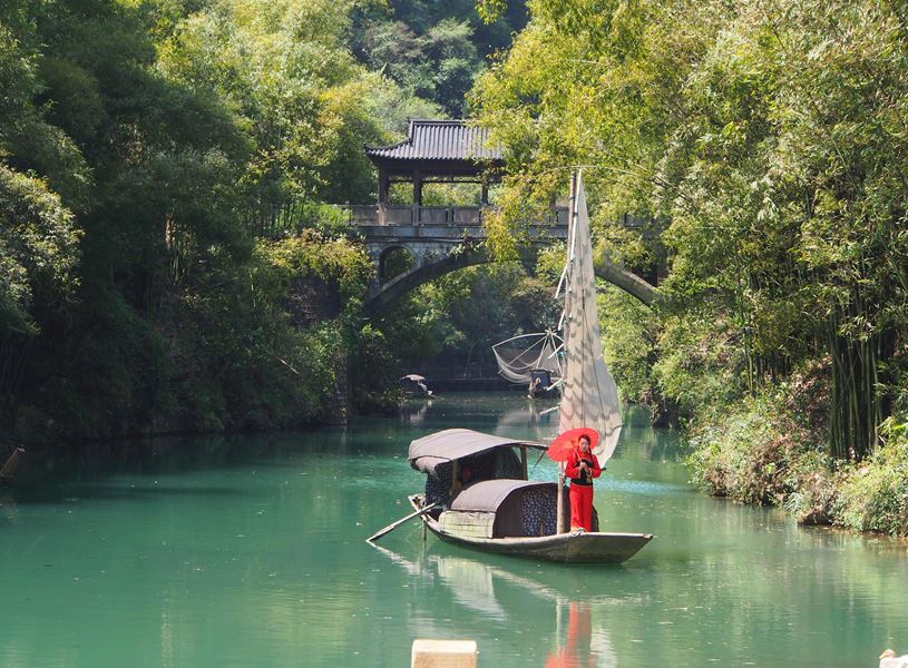 Traditionally dressed woman in red on boat approaching bridge, Yangtze River, China