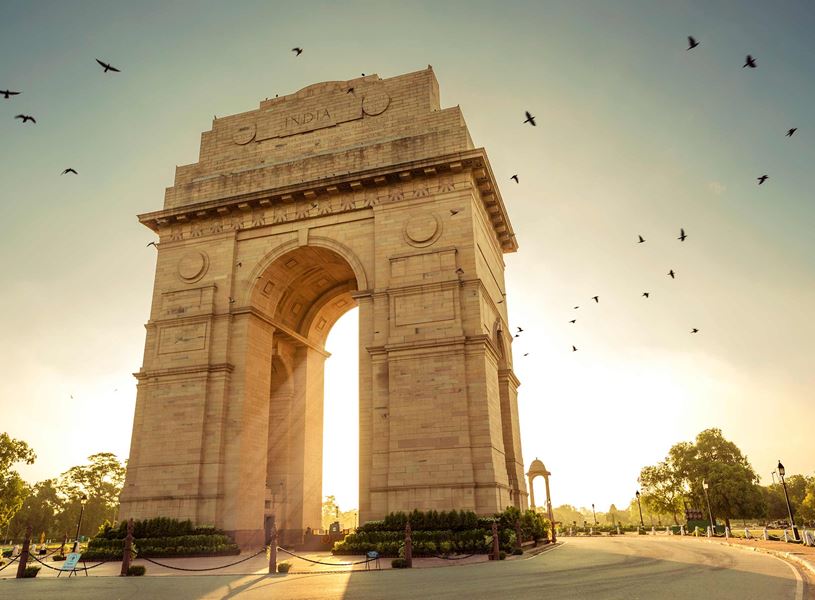 India Gate bathed in sunlight with birds in flight, Delhi, India