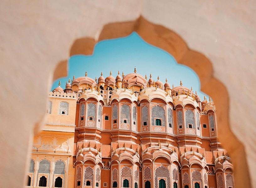 Arched window view overlooking pink sandstone palace of Hawa Mahal, Jaipur, India