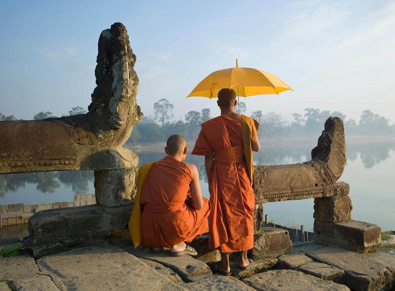 Two Buddhist monks standing by water at Angkor Wat, Cambodia
