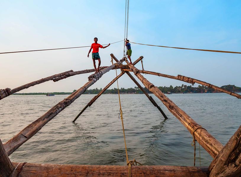 Two young fishermen and chinese fishing nets in Kochi, India