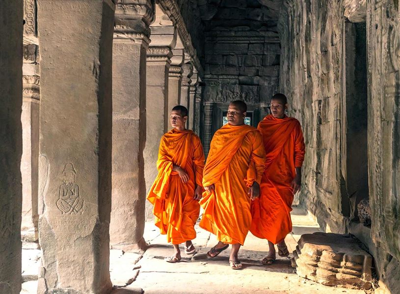 Monks in robes walking between temple columns at Angkor Wat, Cambodia