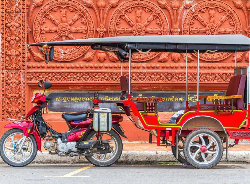 raditional red tuk-tuk parked by a wall in Phnom Penh, Cambodia