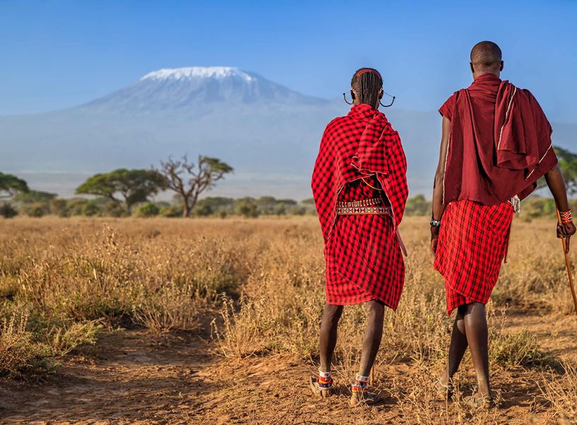 Traditionally dressed warriors from Maasai tribe looking at Mount Kilimanjaro, Kenya, Africa 