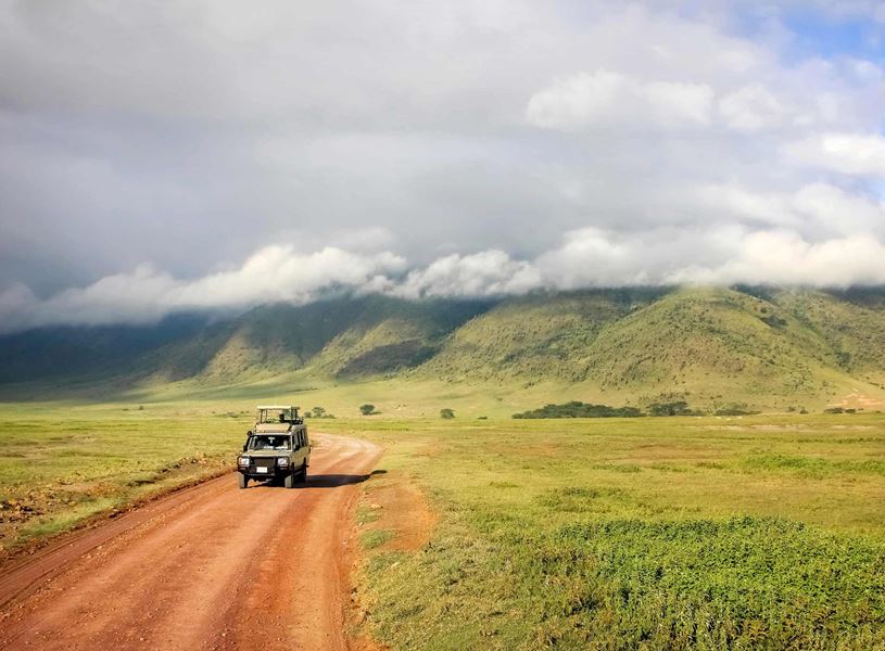 Safari vehicle approaching on dusty road, Ngorongoro Crater National Park, Tanzania