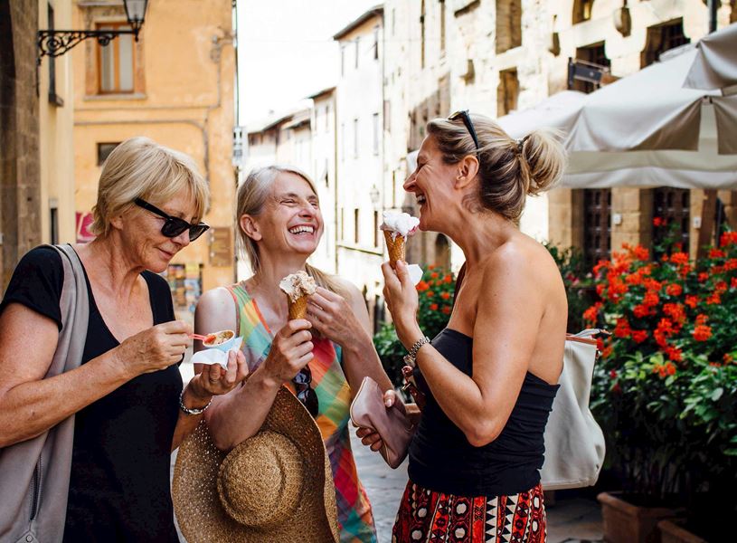 Three travellers enjoying gelato on a cobblestone street