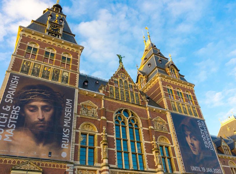 Exterior of Rijksmuseum in Amsterdam with brick facade, towers and large banners